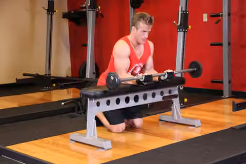 Demonstrasi gerakan Palms-Up Barbell Wrist Curl Over A Bench.