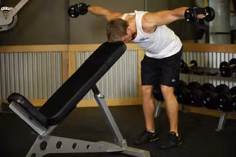 Demonstrasi gerakan Bent Over Dumbbell Rear Delt Raise With Head On Bench.