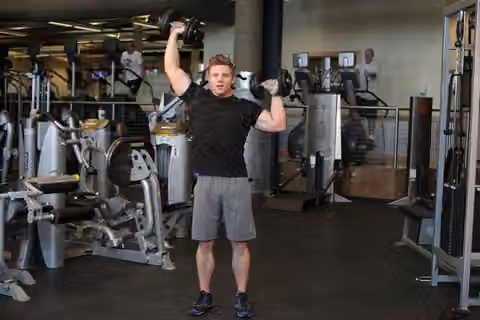 Demonstrasi gerakan Standing Alternating Dumbbell Press.