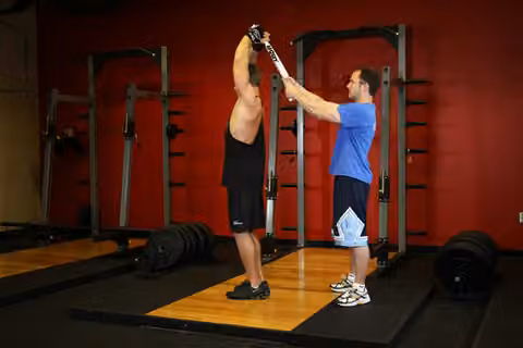 Demonstrasi gerakan Standing Towel Triceps Extension.