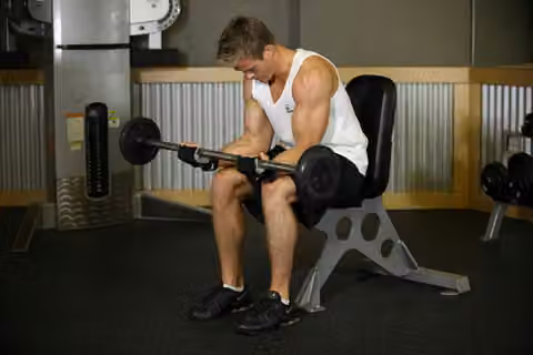 Demonstrasi gerakan Seated Palm-Up Barbell Wrist Curl.